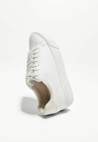 Baskets blanches avec des détails en cuir et en daim, bout rond, design à laçage, semelle texturée et surface supérieure lisse.