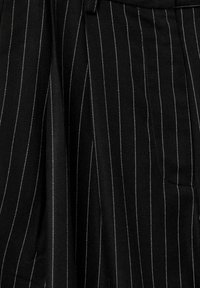 Black fabric with white pinstripes, featuring a textured weave and pleated design. Visible stitching accents around the waistband and pockets.