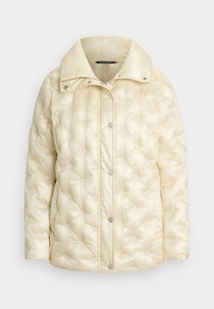 Veste rembourrée de couleur crème avec un col haut, présentant des détails matelassés et des fermetures à pression sur le devant. Texture de tissu douce et brillante.