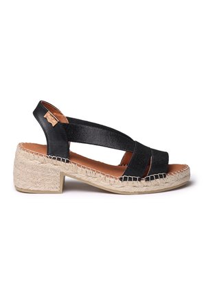 Sandalia estilo espadrille negra con correas anchas, tacón de cuña texturizado y suela de yute natural; cuenta con un acento similar al cuero.