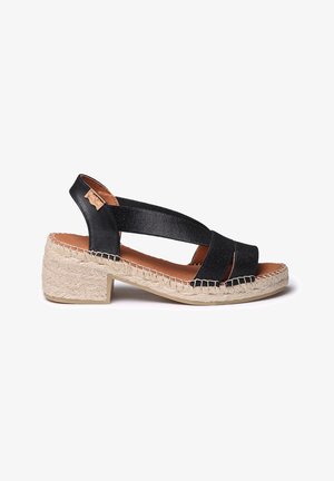 Zwarte espadrille-stijl sandaal met brede banden, een gestructureerde wiggenhak en een natuurlijke jute zool; heeft een leerachtige accent.