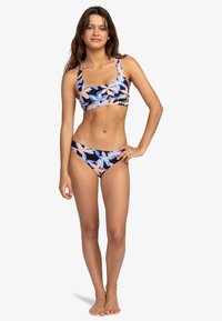 Blumiges zweiteiliges Schwimmanzug in Marineblau mit rosa und blauen tropischen Mustern. BH-Oberteil mit breiten Trägern, Bikini-Unterteil mit einem ähnlichen Design.