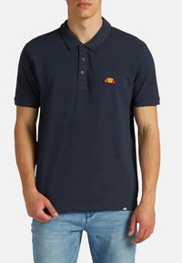 Polo shirt blu navy realizzato in cotone, con una patta a tre bottoni e un piccolo logo ricamato con un design rosso e giallo sul petto.