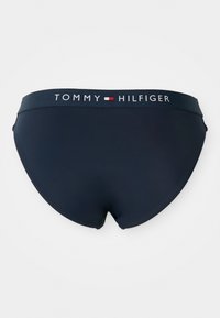 Navy modré bikiny s hladkou textúrou a širokým pásom, s logom "TOMMY HILFIGER" v bielej a červenej farbe.