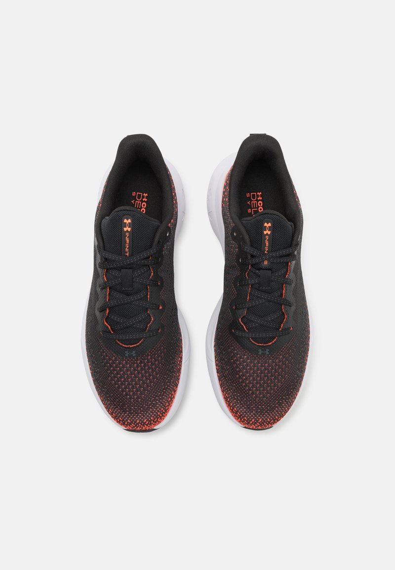 Baskets de sport noires et orange avec une tige en maille, dotées d'une semelle rembourrée, d'un bout rond et de lacets plats. Surface texturée avec de petits motifs.