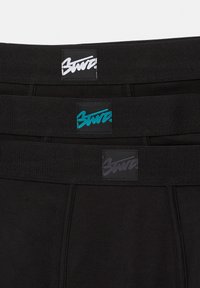 Tri páry čiernych boxerských šortiek s elastickými pásmi, ktoré majú nápisové etikety v bielej a teal farbe. Tkanina vyzerá hladko so šitými švami.