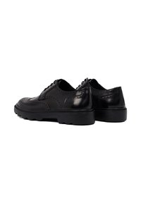 Zwarte leren brogue schoenen met gedetailleerde perforaties, ronde neus en dikke rubberen zool, met opstaande stiksels en vetersluiting.