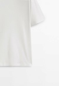 T-shirt blanc uni à manches courtes montré de dos sur fond blanc, mettant en valeur la texture du tissu et les coutures.