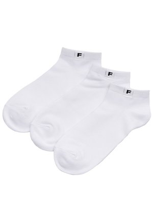 Trzy białe skarpetki do kostki z małą czarną etykietą "F" na mankiecie, ułożone obok siebie na białym tle.