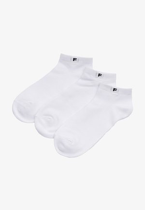 Trzy białe skarpetki do kostki z małą czarną etykietą "F" na mankiecie, ułożone obok siebie na białym tle.