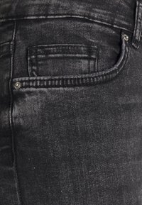  jeans de ganga pretos com um ajuste clássico, textura subtil e um bolso traseiro com um detalhe em botão de metal.