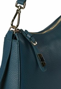 Borsa a mano in pelle verde acqua con superficie strutturata, ferrature dorate e chiusura con cerniera. I dettagli includono una tracolla con clip e accenti decorativi.