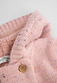 Różowy sweter z dzianiny, wykonany z miękkiej przędzy, z teksturowanym prążkowanym kołnierzem i drewnianym guzikiem z motywem misia.