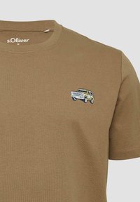 Bruine katoenen t-shirt met een klein geborduurd ontwerp van een voertuig op de borst, ronde halslijn en korte mouwen.