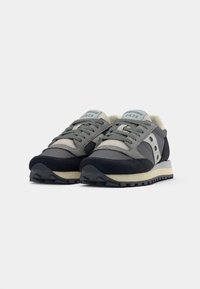 Sneakers Saucony Jazz con una parte superiore grigia e blu navy, materiali in suede e mesh, design con lacci e suola in gomma di colore chiaro.