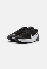 Černé sportovní boty s texturovaným svrškem, bílým logem swoosh a polstrovanou podrážkou s vzorovaným dezénem pro lepší přilnavost.