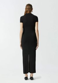 Crna maksi haljina s kratkim rukavima, ovratnikom i prorezom na leđima. Napravljena od glatkog, rastezljivog materijala za priljubljen izgled.