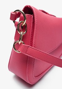 Rosa läderhandväska med en texturerad yta, guldfärgade detaljer och en platt axelrem. Slin, rektangulär design med sömnadsdetaljer.