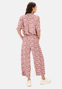 Bloemige jumpsuit in roze en paarse tinten, gemaakt van lichtgewicht stof, met korte mouwen, brede pijpen en een elastische tailleband.
