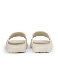 Sandali di gomma beige con un ampio retro aperto e una soletta testurizzata, caratterizzati da una finitura liscia e cinturini laterali rialzati per supporto.