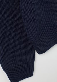 Pull en maille bleu marine foncé avec texture côtelée, couture épaisse et poignets ajustés, mettant en avant un matériau épais et confortable.