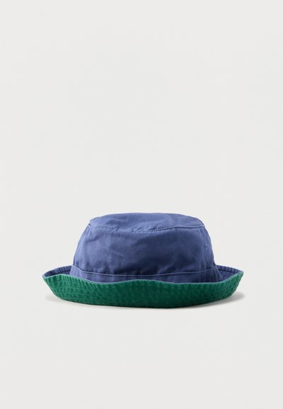 Μπλε καπέλο τύπου κάπα με μαλακό, ελαφρώς τσαλακωμένο ύφασμα και πράσινη, ελαφρώς καμπυλωτή γείσο.