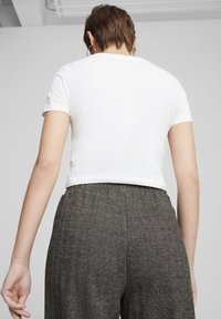 Hvid T-shirt med korte ærmer, der er parret med bukser i mørkt sildemønster, som har en strækbar talje for komfort.
