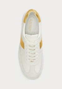 Λευκό δερμάτινο αθλητικό παπούτσι με χρυσή ταινία, στρογγυλή μύτη και λευκές κορδόνες. Μαλακή υφή με λογότυπο στην γλώσσα και στη φτέρνα.