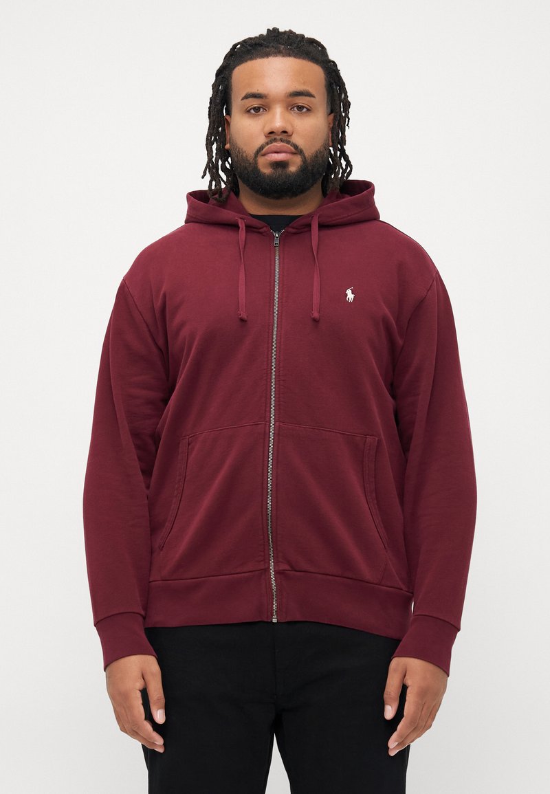 Sweatshirt vinho com fecho éclair à frente, cordão ajustável, bolsos tipo canguru e pequeno logo branco no lado esquerdo do peito, feito de uma mistura suave de algodão.