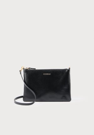 Pochette en cuir noir avec une surface texturée, équipée d'une bandoulière amovible et de ferrures ton or ; le devant affiche le logo "Coccinelle".