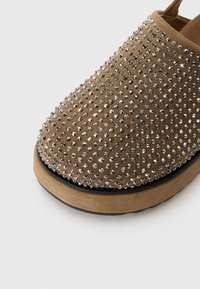 Bruine suède schoenen met een ronde neus, voorzien van een gestippeld ontwerp van zilverkleurige rhinestones en een dikke, beige rubberen zool.