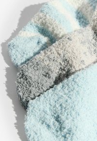 Calcetines de forro polar con textura en azul claro, gris y crema, con un patrón a rayas y material suave y esponjoso.