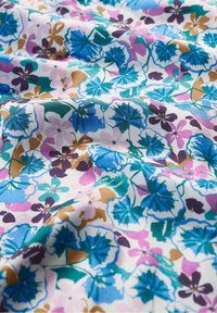 Tessuto di cotone stampato con disegni floreali blu, viola, rosa e verde su uno sfondo bianco, caratterizzato da forme intricate e una texture liscia.