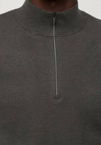 Pull-over en maille grise avec un col montant et une fermeture éclair à moitié au niveau du cou, doté d'une texture lisse et d'une coupe ajustée.