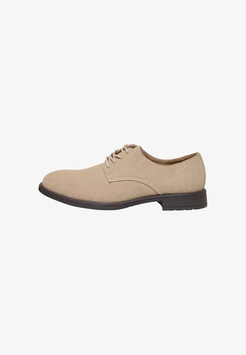 Chaussure habillée en daim beige pour homme avec lacets, semelle noire et petit talon, vue de profil sur fond blanc.