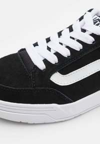 Schwarze Wildledersneaker mit weißen Schnürsenkeln und seitlichem Streifen. Verfügt über ein strukturiertes Obermaterial, gepolsterten Schaft und eine Gummisohle mit gerippter Musterung.