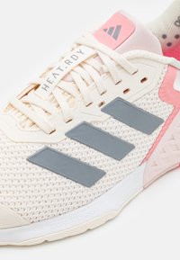 Beige sportssko med grå tre-stribe logo, mesh-overdel, rosa accenter og tekstureret sål. Har "HEAT.RDY" label på tungen.