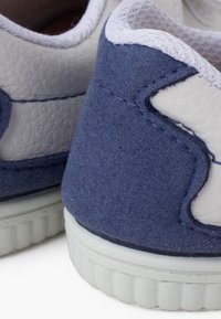 Sneaker in suede blu e pelle bianca con dettagli testurizzati, suola in gomma e cuciture a contrasto lungo i bordi.