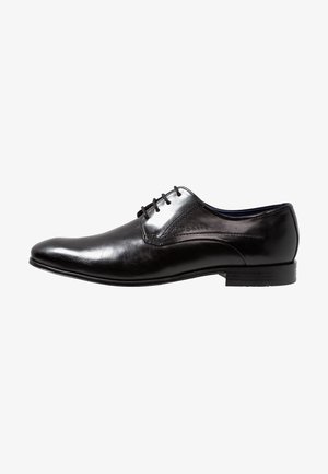 Chaussure formelle pour homme en cuir noir poli avec lacets et petit talon, présentée en profil latéral sur fond blanc.