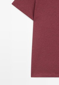 Kreppfarbendes kurzärmliges T-Shirt aus Baumwolle. Weiche Textur mit leichtem Melange-Muster. Gerader Saum und sauber genähte Ärmel.