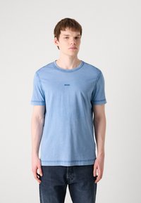 T-shirt de algodão azul claro com decote redondo e mangas curtas. Apresenta um pequeno logo 'BOSS' em azul escuro no peito. Corte clássico.