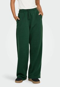Grønne, vide sweatpants lavet af blødt, tekstureret stof. Funktionen inkluderer en elastisk talje med snoretræk og sidelommer.