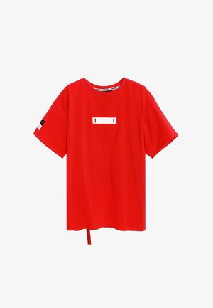 Camiseta roja de manga corta hecha de algodón. Presenta un parche rectangular blanco en la parte frontal y una cinta de tela en la parte inferior izquierda.