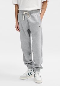 Grijze joggingsbroek van zacht materiaal, met een elastische tailleband met trekkoord, zijzakken en een strakke manchette bij de enkels.