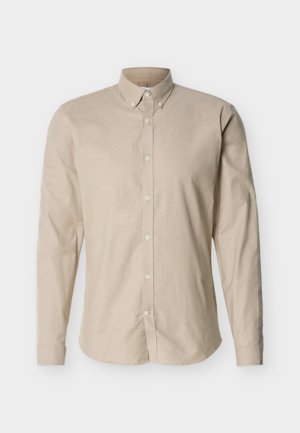 Beige langærmet skjorte med knapper og button-down krave samt en tætsiddende silhuet, vist på en neutral baggrund.