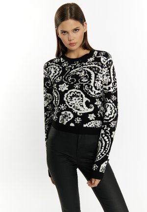 Fekete-fehér cropped pulóver, amely paisley mintával rendelkezik, kötött textúrájú, kerek nyakú és hosszú ujjú, fekete testre simuló nadrággal párosítva.