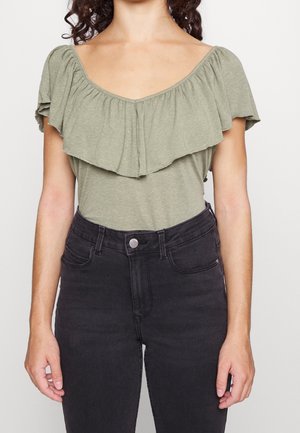 Olive green top with a ruffled neckline and short sleeves, paired with high-waisted black jeans; soft fabric, relaxed fit.