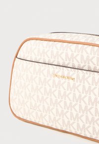 Valge riidest kosmeetikakott, millel on korduv "MK" muster, pruunid aktsendid ja kuldne "Michael Kors" logo esiplaanil. Ristkülikukujuline.