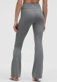 Harmaat leveälahkeiset legginsit korkealla vyötäröllä, valmistettu sileästä ja joustavasta kankaasta. Sisältää sauman yksityiskohtia takana ja lanteilla.