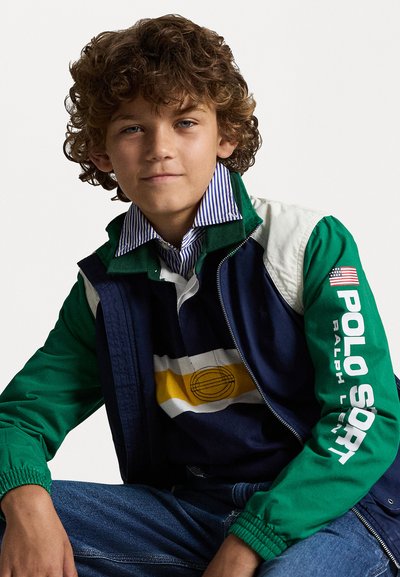 Νεανικό μπουφάν με πράσινα μανίκια, ναυτικό σώμα και ριγέ γιακά. Διαθέτει λευκή και κίτρινη οριζόντια ριγέ σχέδια στο στήθος.